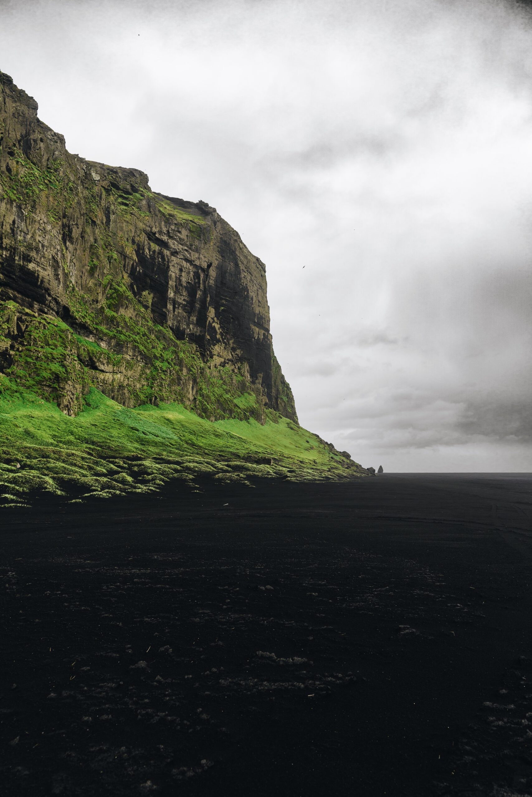  Djordje Vukojicic Photography reveals the rugged beauty of a rocky cliff adorned with grass, overlooking a peaceful body of water, creating a harmonious blend of elements.