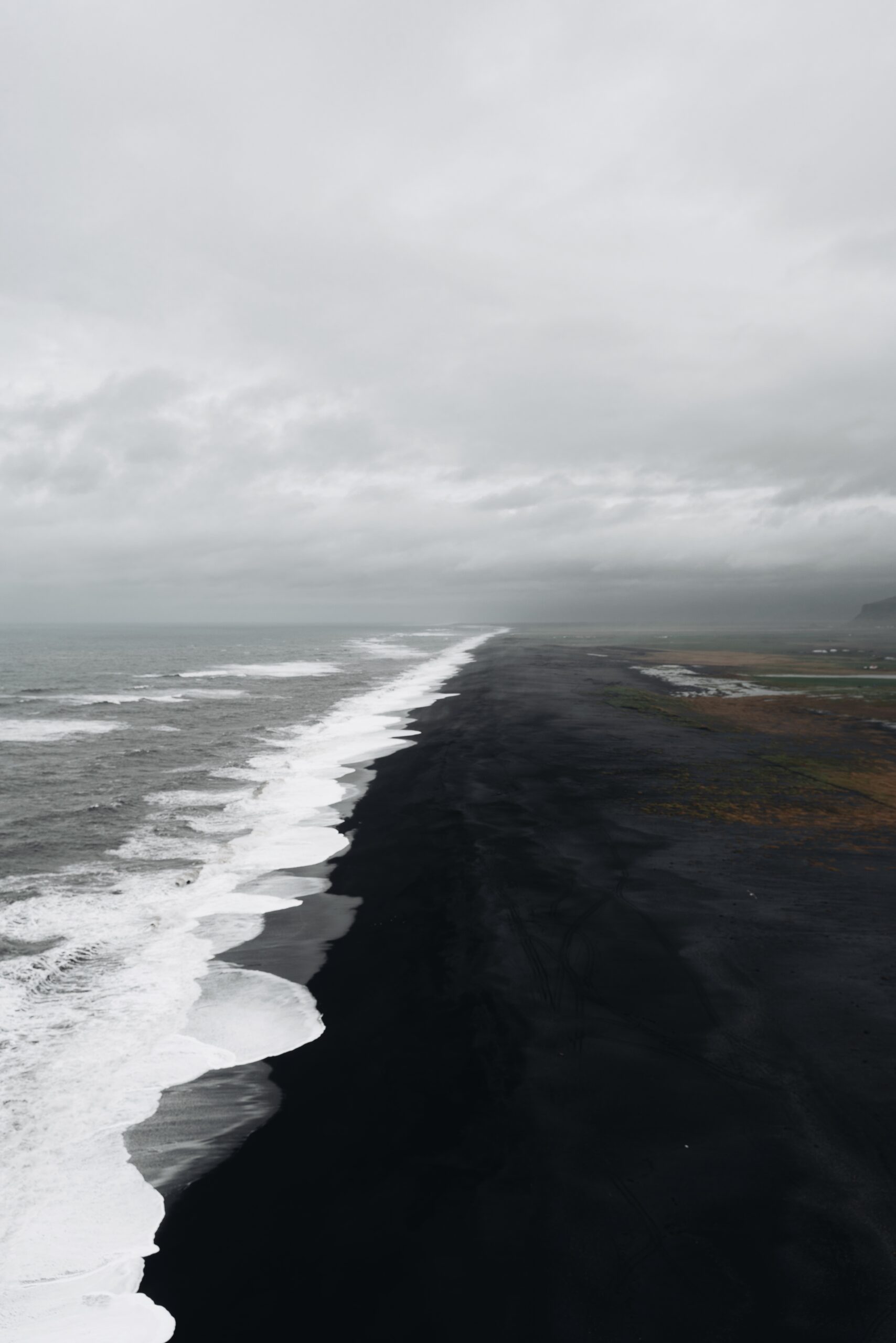  Immerse yourself in the serenity captured by Djordje Vukojicic Photography - behold the contrast of a black sand beach adorned with white foam along the shore.