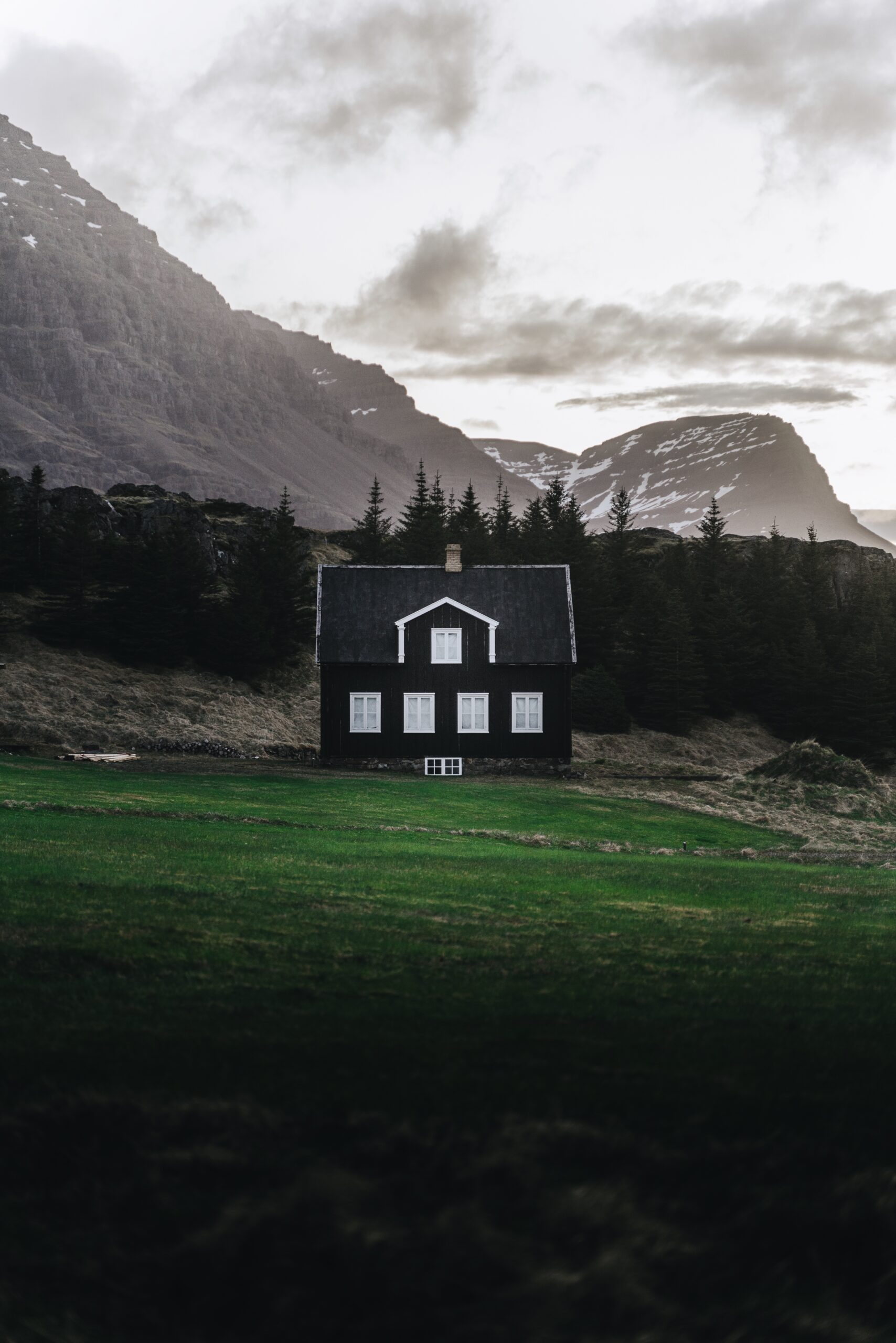  Embrace the tranquility of rural landscapes with Djordje Vukojicic Photography - a charming house nestled in a field, framed by the towering presence of distant mountains.