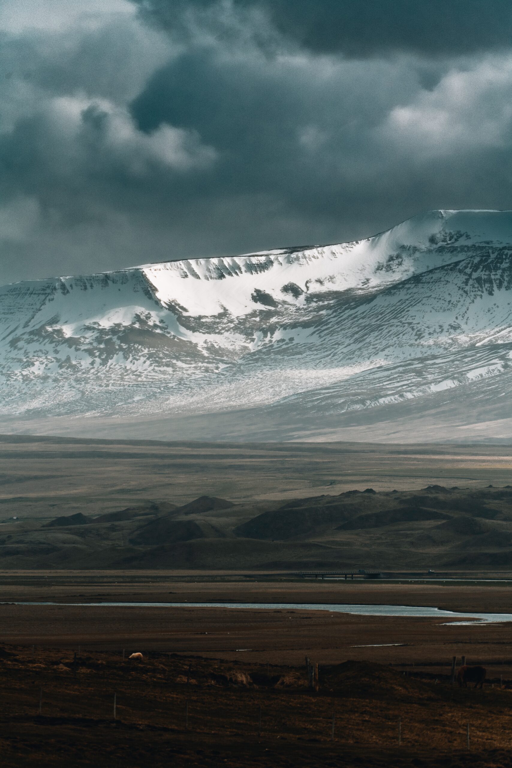 Witness the serene elegance of snow-capped peaks through Djordje Vukojicic Photography - a distant snowy mountain framed against a tranquil landscape.